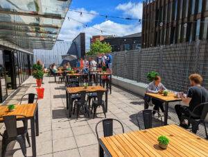 group of people sat outside drinking on the liverpool escape live roof terrace