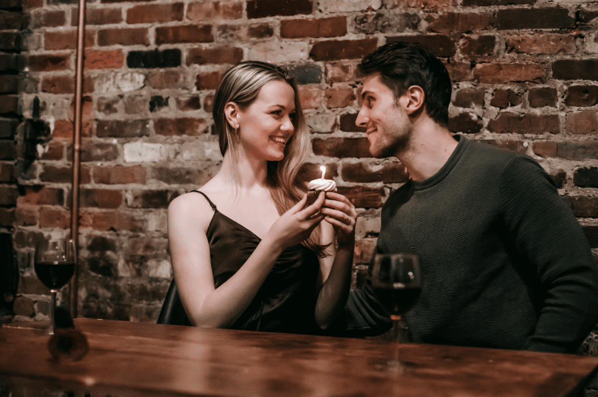 Attracted couple gazing romantically at eachother with a small cake and candle.