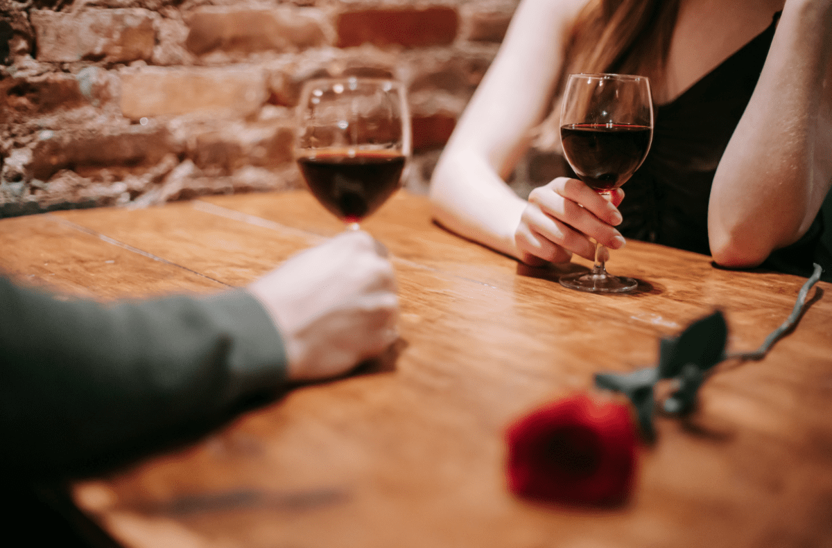 Date couple sat at a table with glasses of red wine
